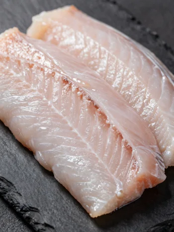 木製のまな板に乗った新鮮な鰻のフィレとスパイス