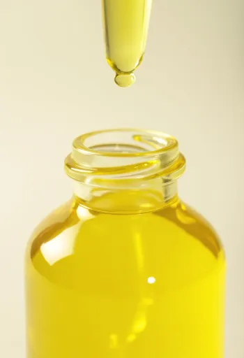 小瓶に入ったレモンオイルと、新鮮なレモンスライス、レモンの皮