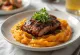 フレッシュパセリを添えて盛り付けられたBBQ豚肩ロースとサツマイモのピューレ