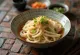 きしめん、濃厚なだし汁、新鮮な青ネギといりごまを添えた平打ちうどん